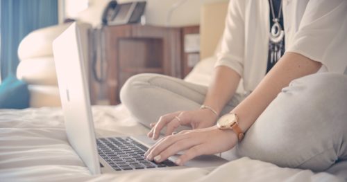 ベッドの上でパソコンを使用している女性の写真